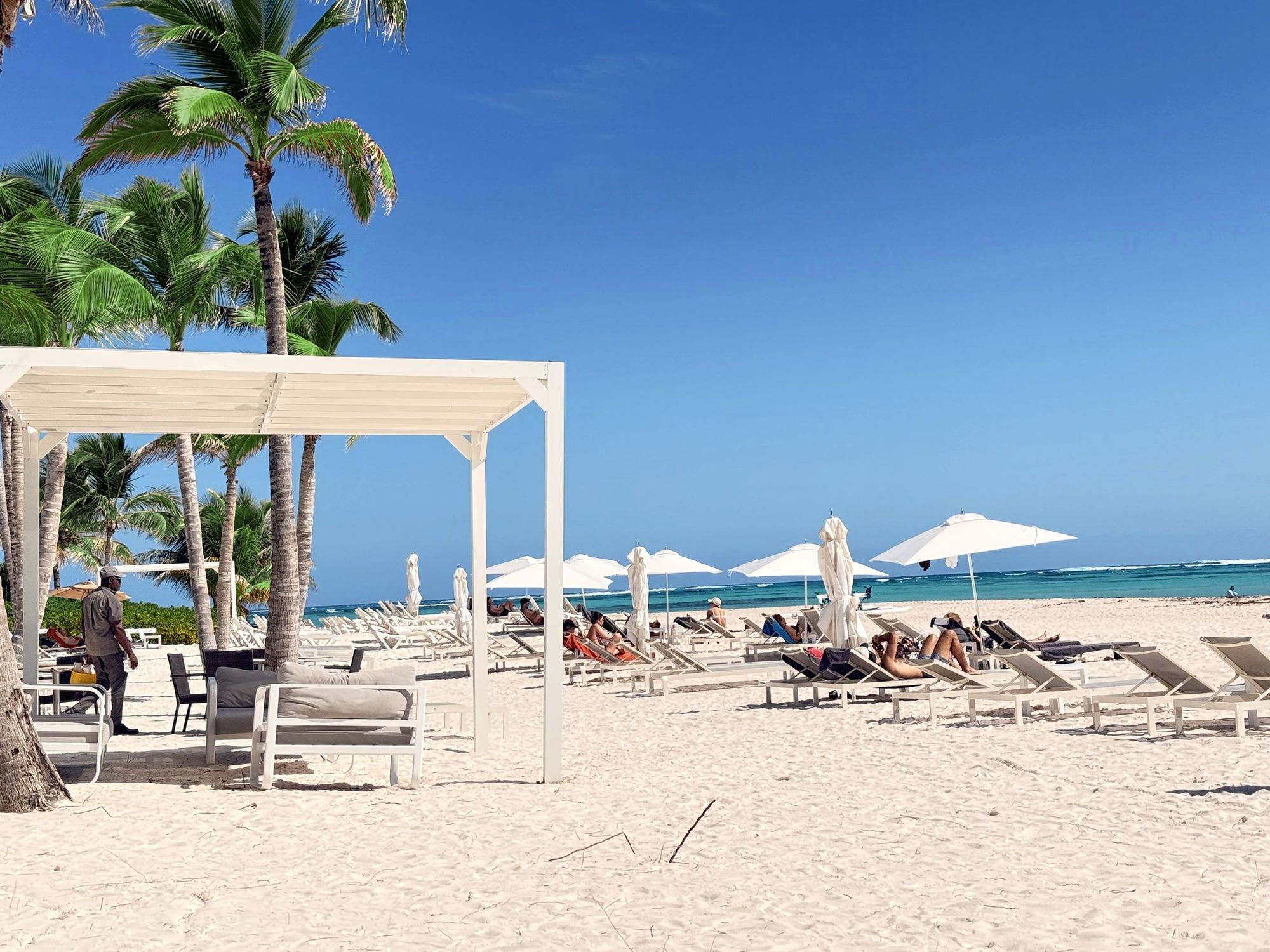White-sand beach with palm trees, umbrellas and turquoise water